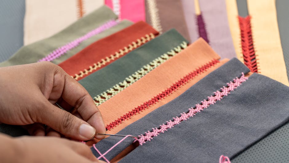 Hands adding embroidered detail to richly coloured ceremonial textile work.