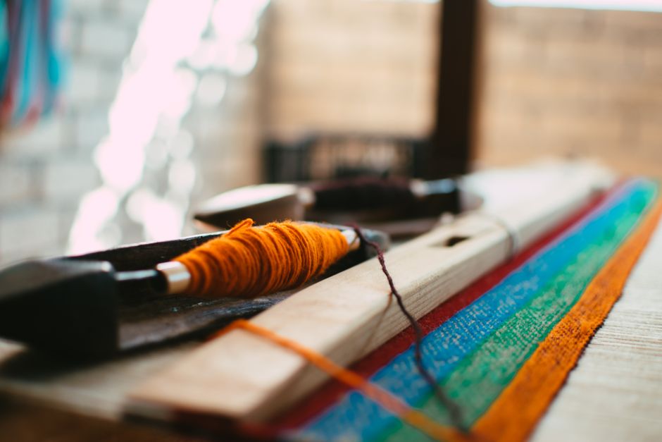 A vibrant close-up of weaving equipment and multicolored threads showcasing craft in focus.
