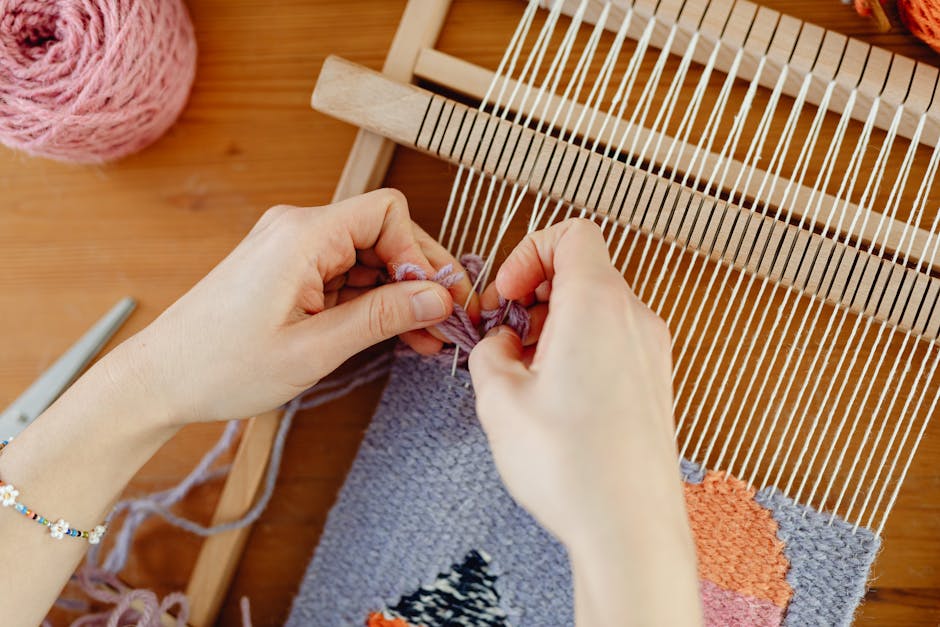 Close-up of hands working with coloured textile materials using traditional workshop equipment.